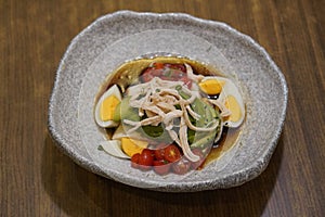 top view hot avocado slice, shredded chicken, boiled egg silce, tomatos slice on white and black ceramic bowl on wooden table