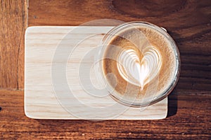 Top view of hot cappuccino coffee cup on wooden tray with heart