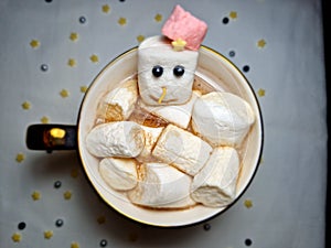 Top view of hot chocolate with snowman-marshmallows in a cup with a snowflake