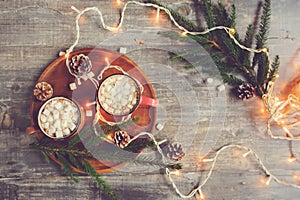 top view of hot cocoa with marshmallows on rustic wooden table with christmas lights