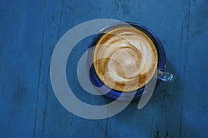Top view of hot coffee cappuccino cup on blue painted wood table