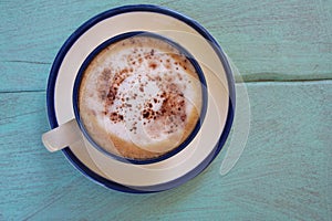 Top view of hot coffee  cappuccino cup or hot drink cocoa with milk foam and cinnamon powder on light blue pastel painted wood