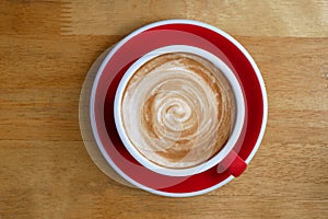 Top view of hot coffee cappuccino latte cup on red ceramic sauce