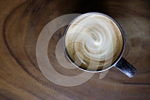 Top view of hot coffee cappuccino latte cup with spiral milk foam on wood texture table background