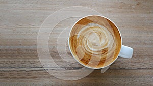Top view hot coffee cappuccino latte spiral milk foam on wooden background