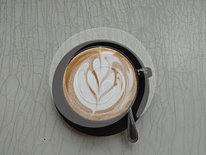 Top view of hot coffee cappuccino spiral foam isolated on gray background