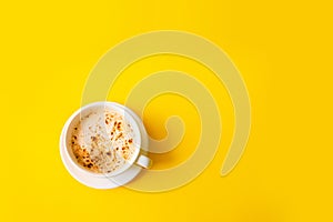 Top view of hot coffee cappuccino on yellow background. Minimal, flat lay concept