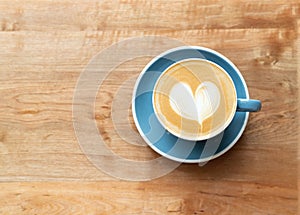 Top view of hot Coffee cup with a barista art heart shape foam on wooden table