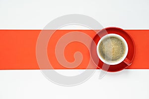 top view of hot coffee cup in red ceramic mug on red round ceramic plate, placed on red and white background with copy space