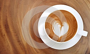 Top view of hot coffee latte art heart shape foam on wood table