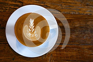 Top view of hot coffee latte cup with milk foam latte art texture on rustic wood table background.