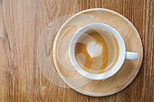 Top view of hot coffee latte cup with mini heart shaped milk foam on wood texture background, minimal love concept.