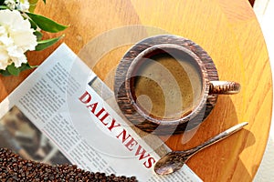 Top view of hot fresh espresso coffee in the wooden cup with newspaper and coffee beans on wooden table background. Morning