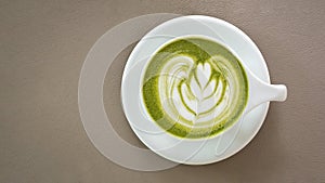 Top view of hot matcha green tea latte art foam beige color leather background