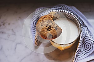 Top view of hot milk in a glass and a chocolate chip cookie