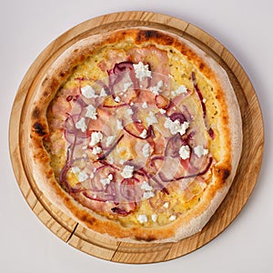 Top view of hot pizza on a wooden stand.