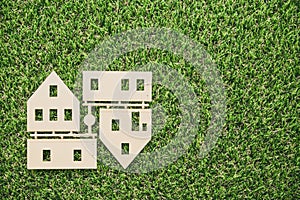 Top view of house model parts on green artificial grass background with copy space. Money saving plan for house remodel, home loan