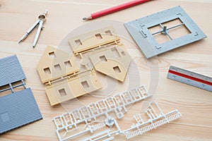 Top view of house model, pencil, ruler and dividers on wooden architects table. Creative home design and construction