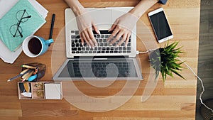 Top view of human hands touching laptop keyboard typing in office