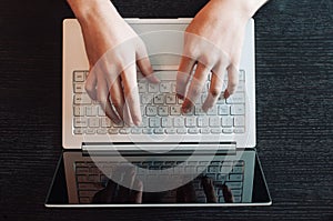 Top view of human hands typing on laptop