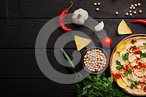 Top view of hummus ingredients. Yellow hummus and chips on a wooden background. Hummus preparation concept. Copy space.