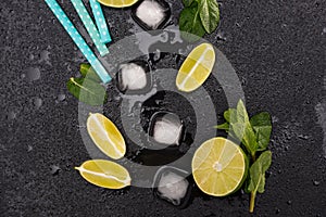 Top view of ice cubes and mojito cocktail ingredients on black slate board cocktail
