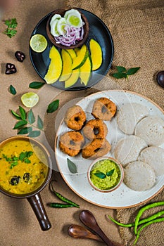 Top view of Idli, Wada, Sambar and Chutney. Traditional South Indian food, surrounded with lemon, raw mango and green chillies
