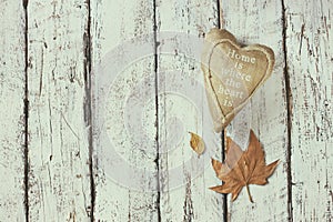 Top view image of autumn leaves and fabric heart over wooden textured background. copy space