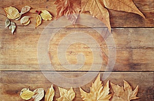 Top view image of autumn leaves over wooden textured background