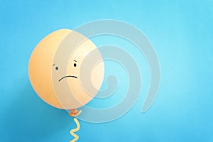 Top view image of balloon with sad face over blue background. Concept of emotions and sadness or stress