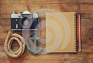 Top view image of blank notebook, nautical rope, anchor and camera. travel and adventure concept. retro filtered image