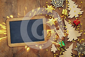 Top view image of christmas festive decorations next to empty blackboard on old wooden background