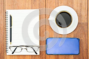 Top view image of coffee cup and cellphone on wooden table