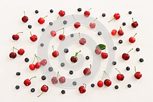 Top view image of colorful assorted mix of berries, blueberry and sweet cherry over wooden white background