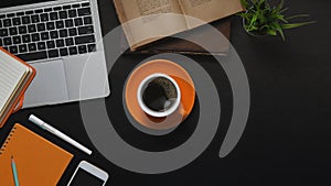 Top view image of Computer laptop, Coffee cup, Books, Potted plant, Notebook, Diary, Pen and Smartphone.