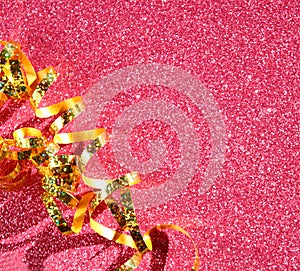 Top view image of curly golden ribbon over textured pink shiny background