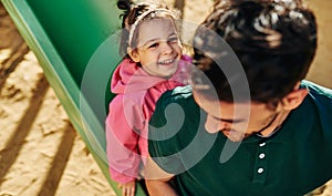 Top view image of cute happy kid daughter playing with her father outdoors. Handsome dad and toddler little girl laughing and