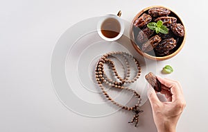 Top view image of decoration Ramadan Kareem background,  hands picking up dates fruit, tea and rosary beads. Flat lay background