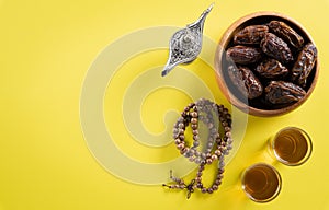 Top view image of decoration Ramadan Kareem,  dates fruit, aladdin lamp and rosary beads on yellow  background. Flat lay with copy