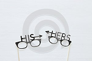 Top view image of funny and colorful photo booth props with text: HIS, HERS for party or wedding over white background.