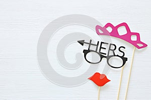 Top view image of funny photo booth props with text: HERS for party or wedding over white background.