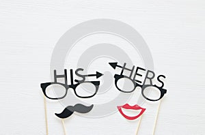 Top view image of funny photo booth props with text: HIS, HERS for party or wedding over white background. photo