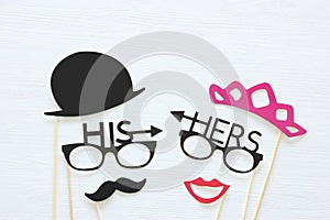 Top view image of funny photo booth props with text: HIS, HERS for party or wedding over white background.