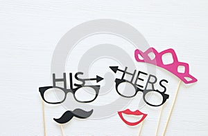 Top view image of funny photo booth props with text: HIS, HERS for party or wedding over white background.