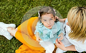 Top view image of happy kid playing with her mother, enjoying the time together outdoors.