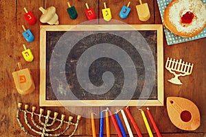 Top view image of jewish holiday Hanukkah with menorah (traditional Candelabra), donuts and wooden dreidels (spinning top)