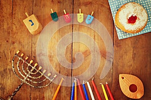 Top view image of jewish holiday Hanukkah with menorah (traditional Candelabra), donuts and wooden dreidels (spinning top)