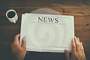 top view image of male hand holding blank Newspaper with empty space to add news or text. retro style image.