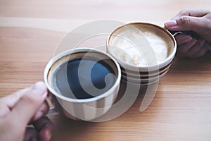 Top view image of man and woman`s hands holding coffee cups with wooden table