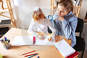 Top view image of mother helping her daughter with homework, doing drawings